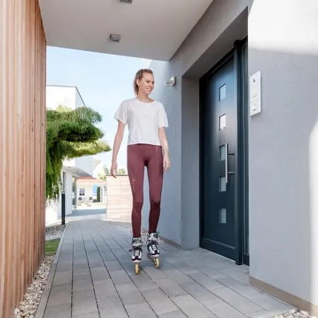 Eine Frau mit Rollschuhen und ohne Taschen kommt nachhause zu ihrer Tür mit Fingerprint Zugang